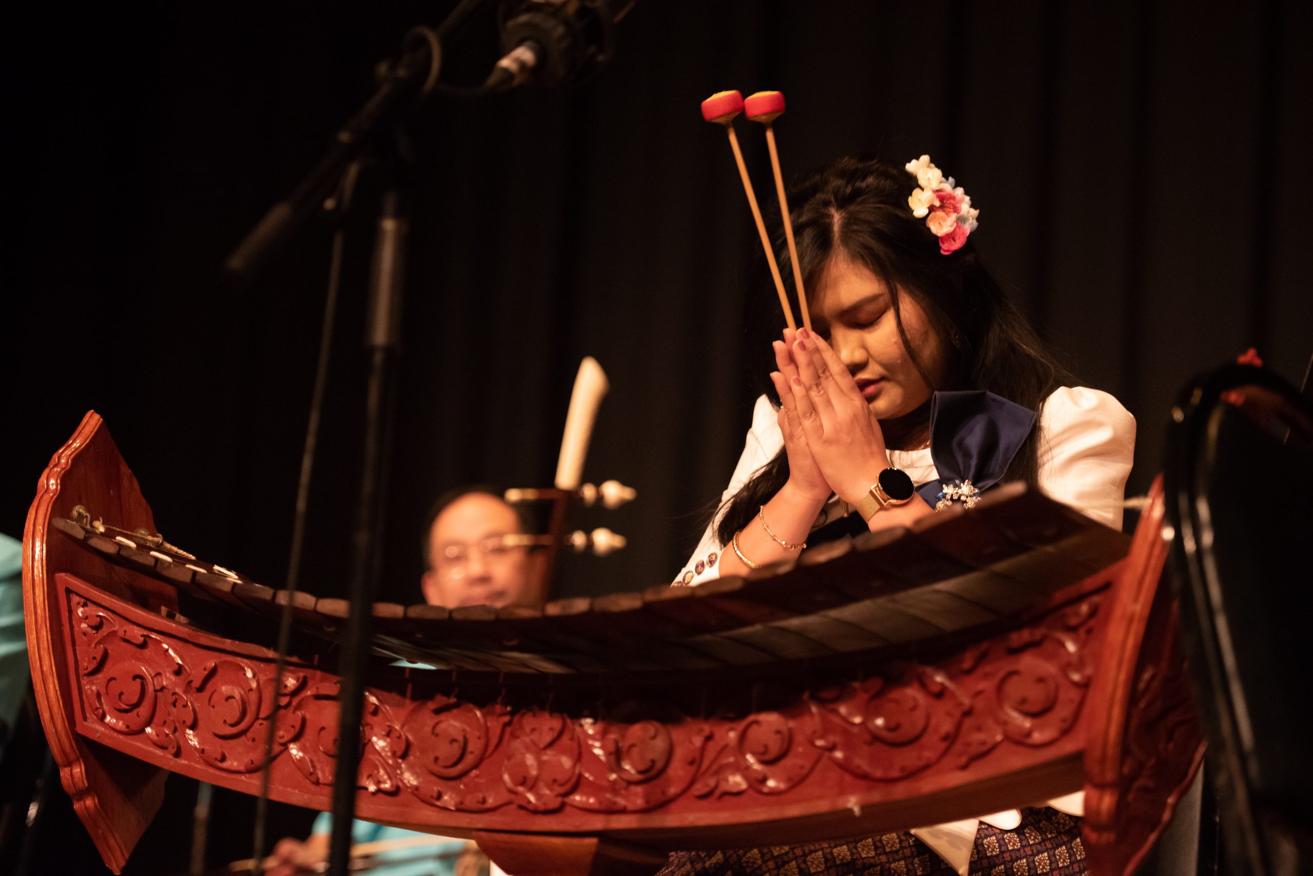 Asian woman praying with small mallets in hand